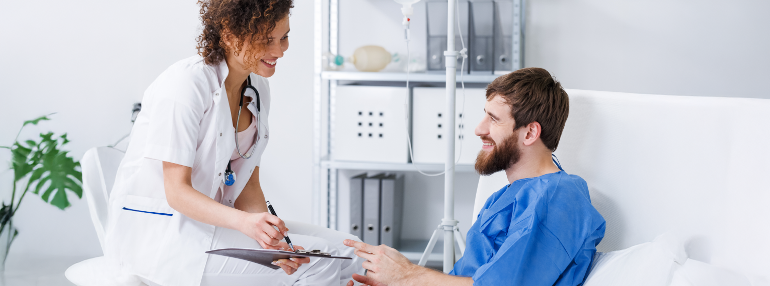 Ein Patient im Krankenbett spricht mit einer Ärztin.