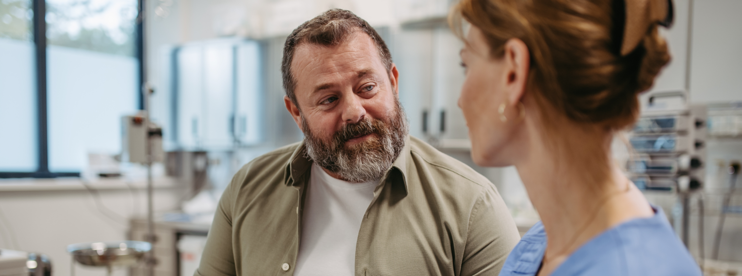 Ein Patient spricht mit seiner Ärztin im Untersuchungszimmer.