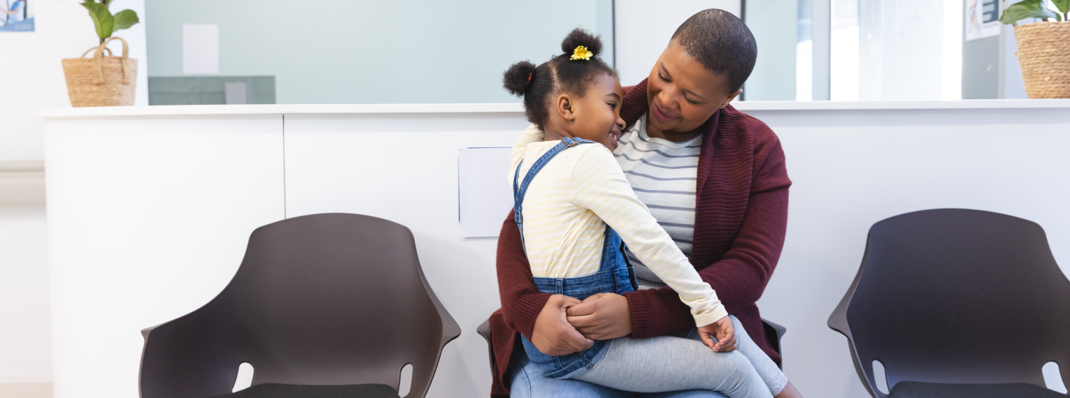 Eine Mutter sitzt mit ihrem Kind im Wartezimmer einer Arztpraxis.