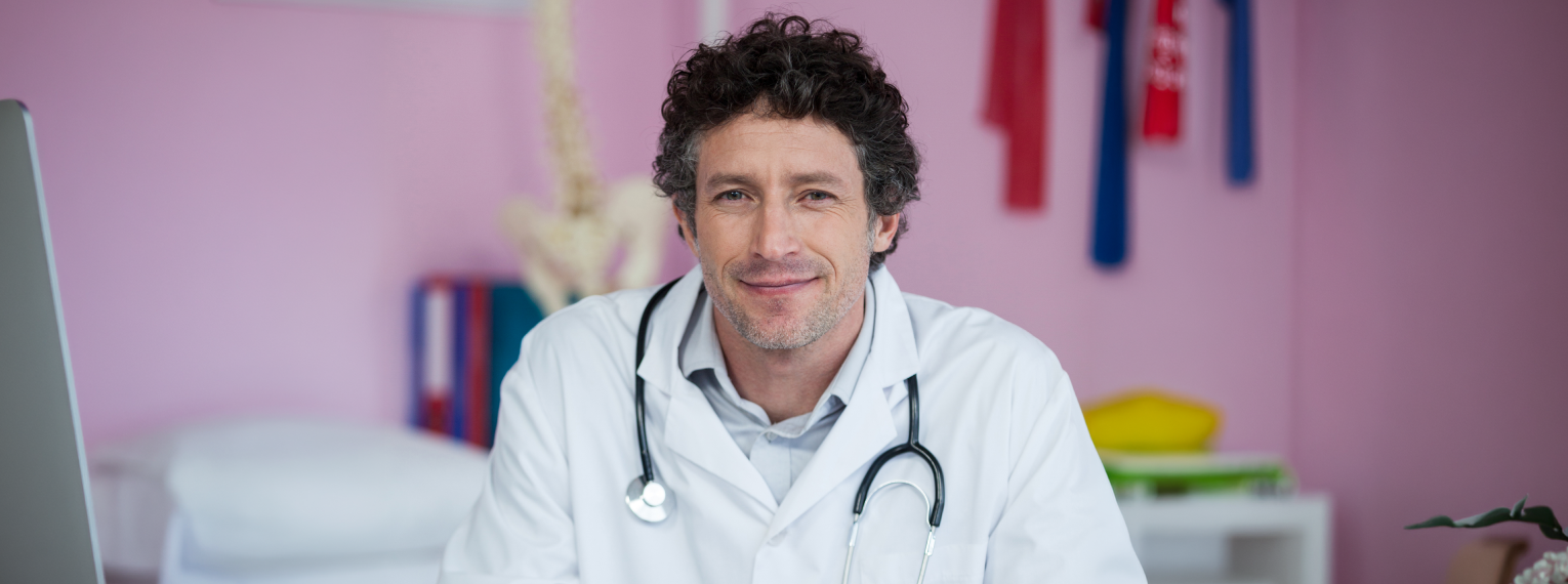 Ein Chiropraktiker schaut in die Kamera und lächelt.