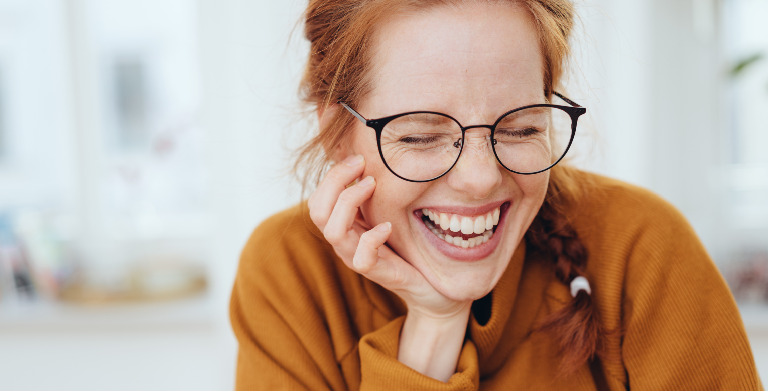 Eine Frau mit Brille lacht.