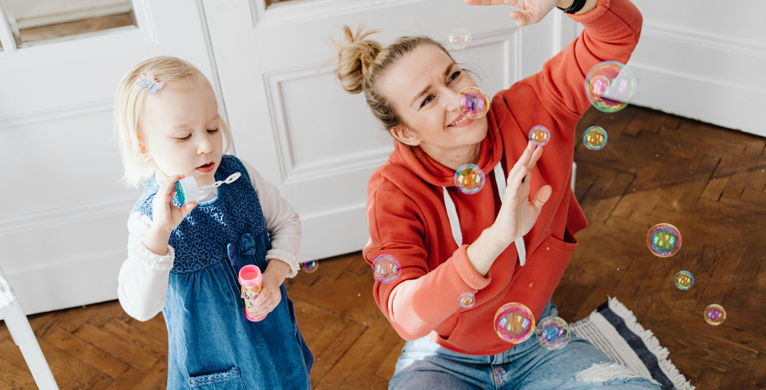 Mutter und Tochter spielen mit Seifenblasen.
