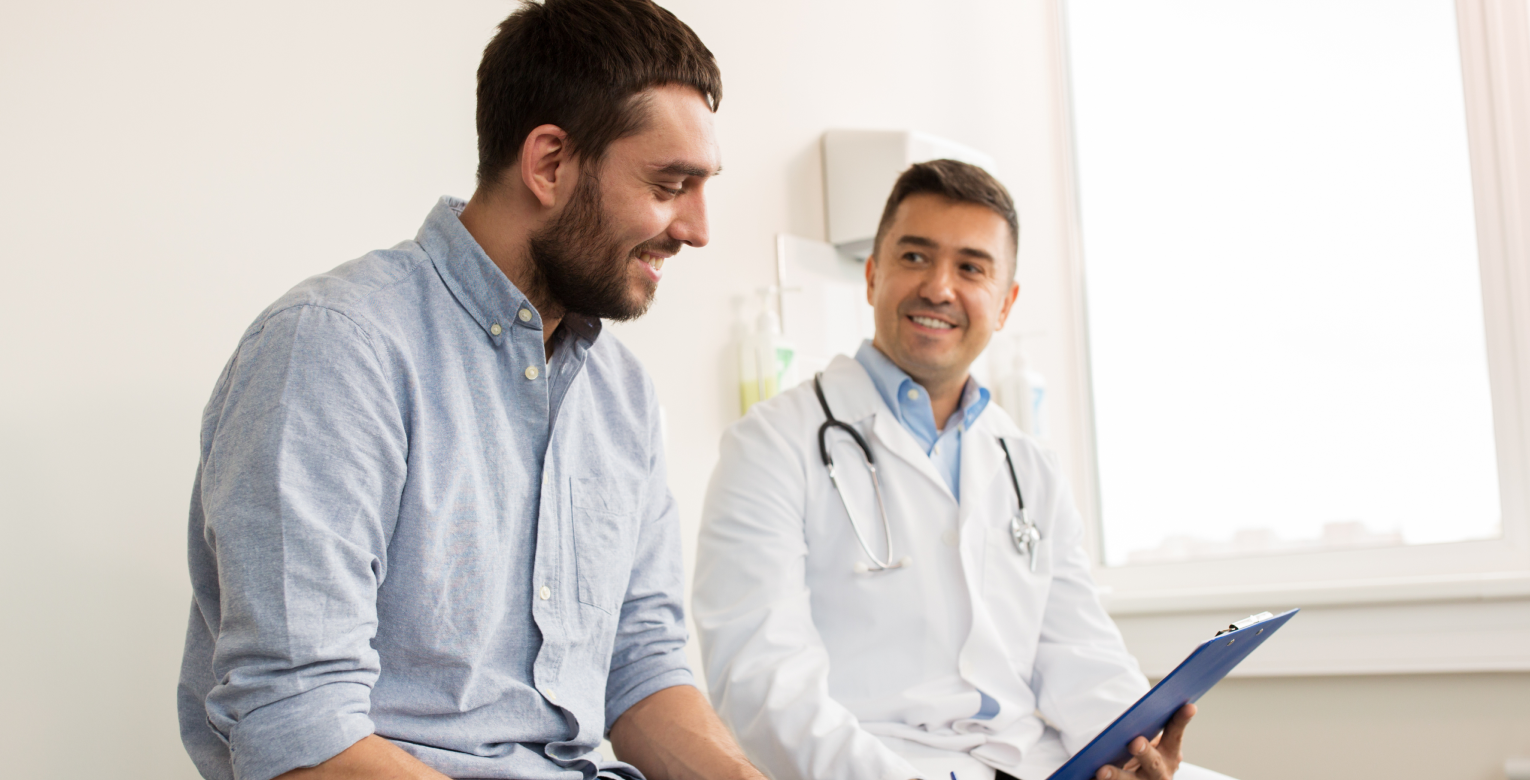 Ein Arzt spricht mit eine Patient in einem Untersuchungszimmer.